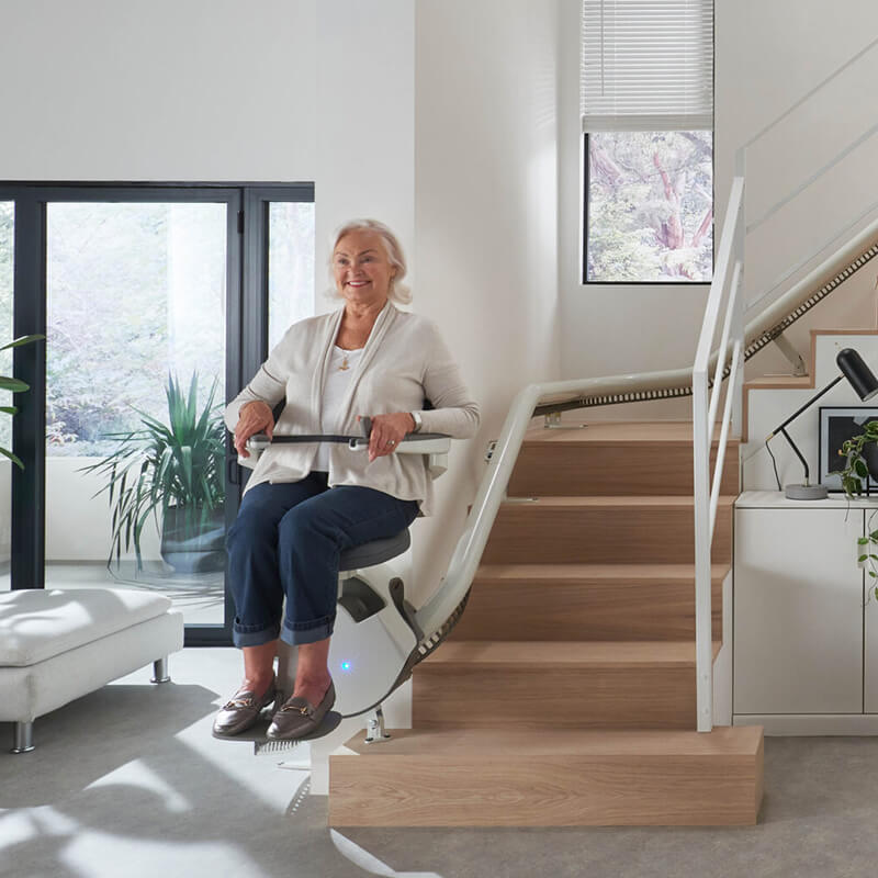 Ältere Dame auf Sitzlift - Treppenlift Modell Flow X von Access 1 Rohrsystem